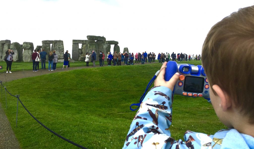 Child taking picture of Stonehenge with visitors